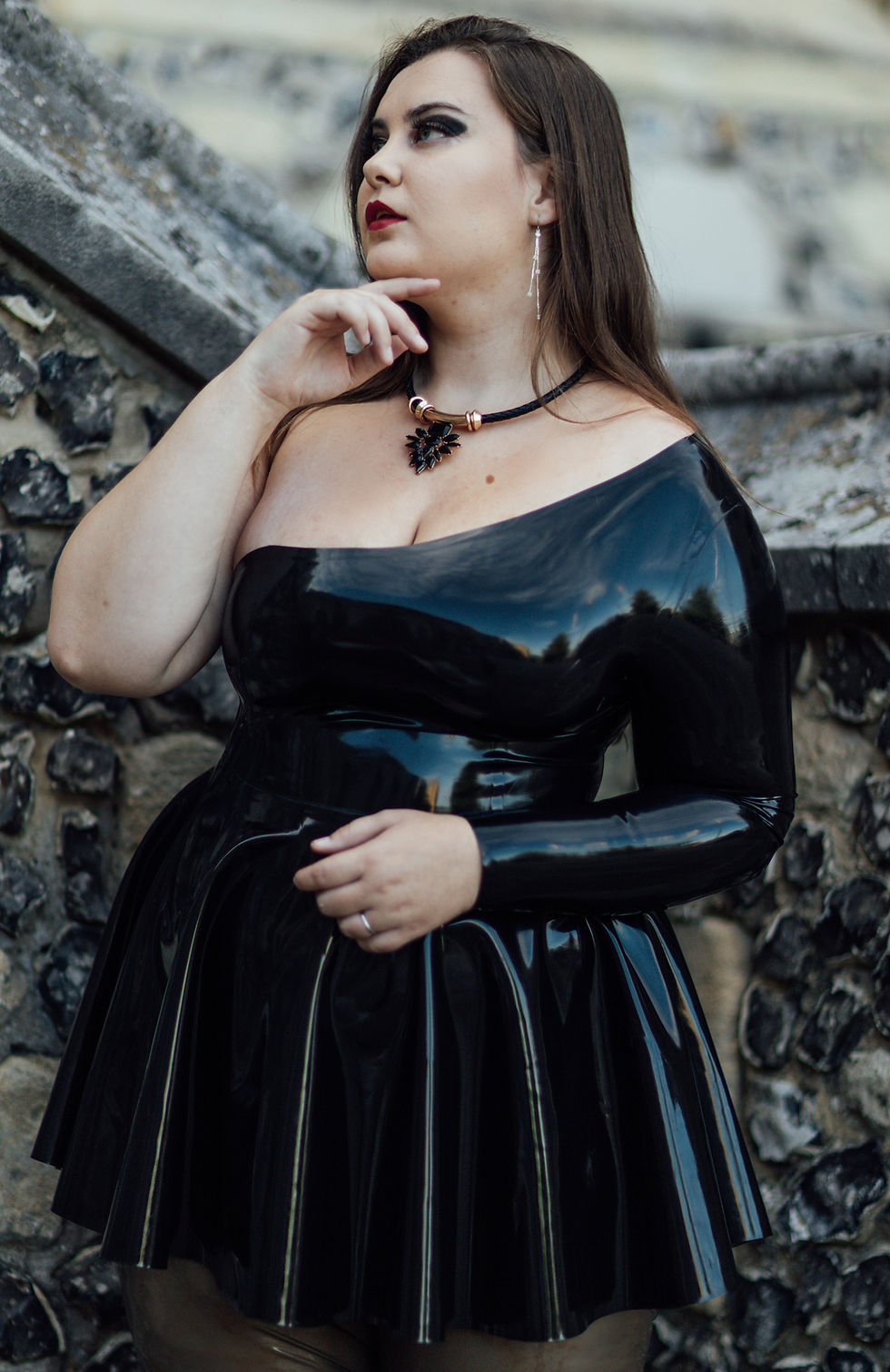 latex dress being shown in black with one off shoulder design and one full length sleeve fitted torso and flared skirt