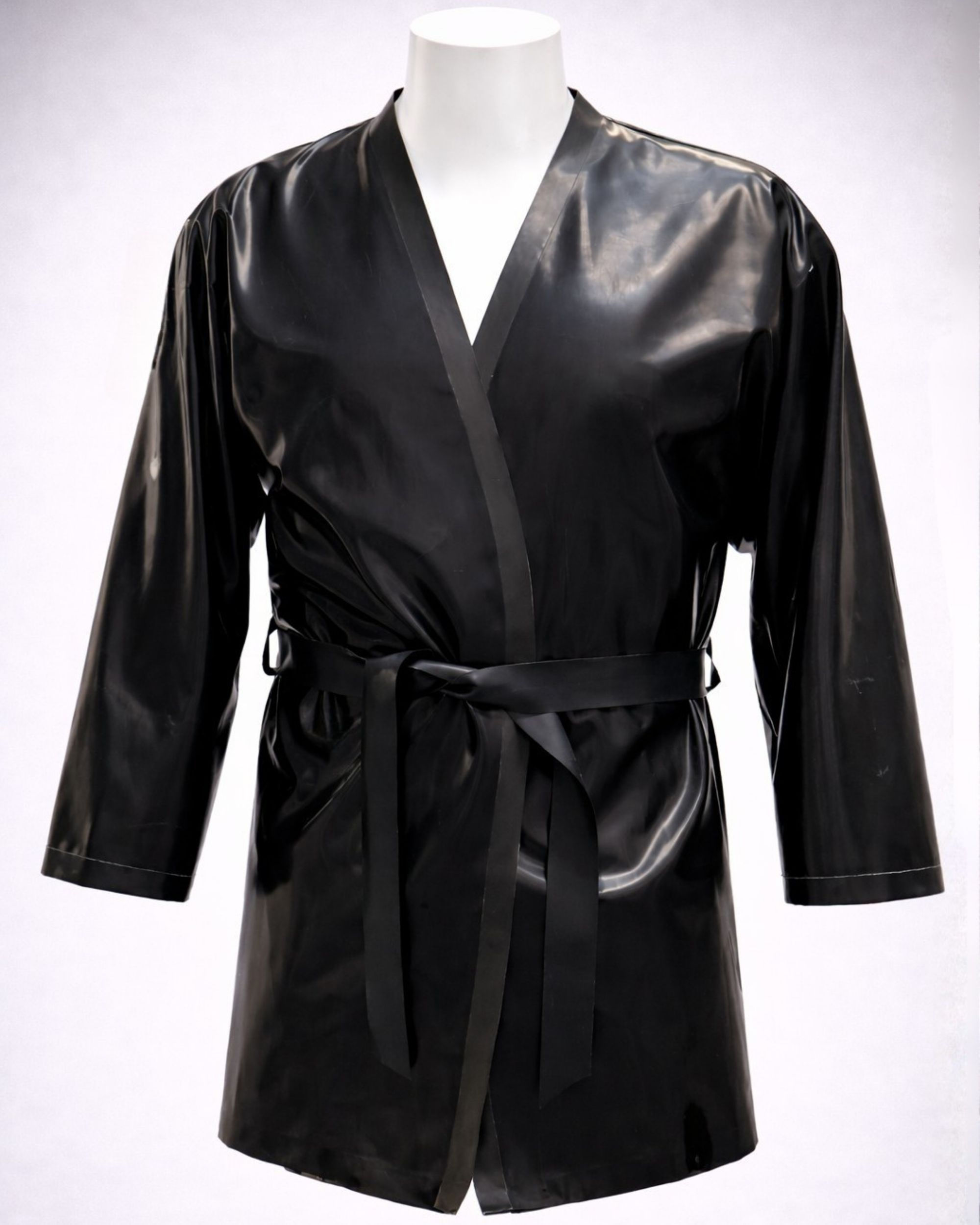 mannequin wearing a black latex smoking jacket with a belted waist, relaxed sleeves, and a short hemline, styled against a p