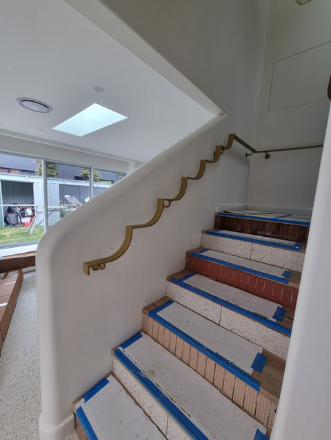 White staircase with gold handrail and protective tape, interior design, custom metal fabrication service