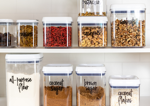 Various pantry items in clear storage containers neatly line two shelves.