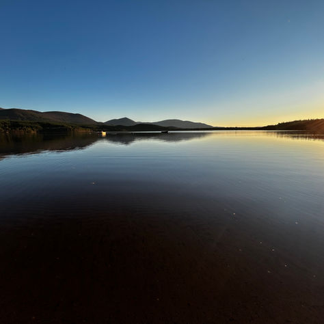golden sunset on still loch, mirror reflection on loch Morlich