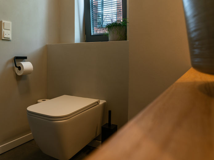 WC-Bereich mit zurückhaltender Beleuchtung und Holzdetails, ruhige Farbgebung von NIC interior.