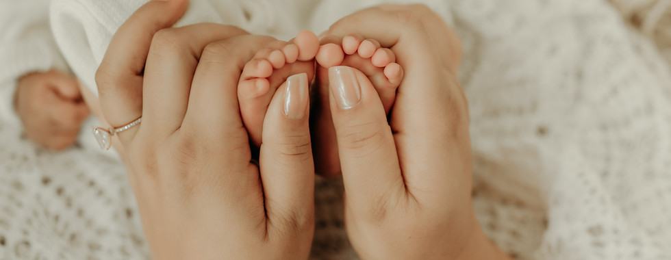 Close-up detail photo of newborn baby feet held by parents during a Maple Grove newborn photography session
