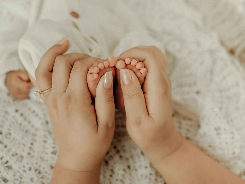 Parents holding newborn baby feet during a luxury newborn photography session at Elsiebel Photography serving Burnsville, Minneapolis, Edina, Eden Prairie, Maple Grove, and surrounding areas