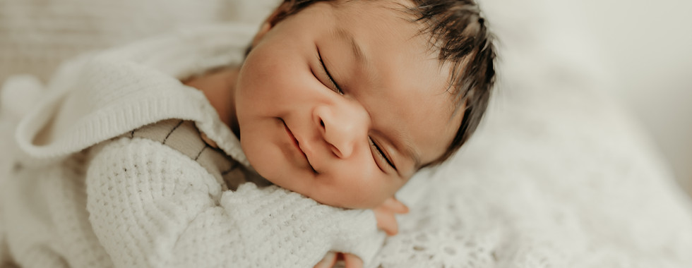 Sleeping newborn baby boy posed on a cream blanket with soft natural light in Elsiebel Photography studio near Maple Grove