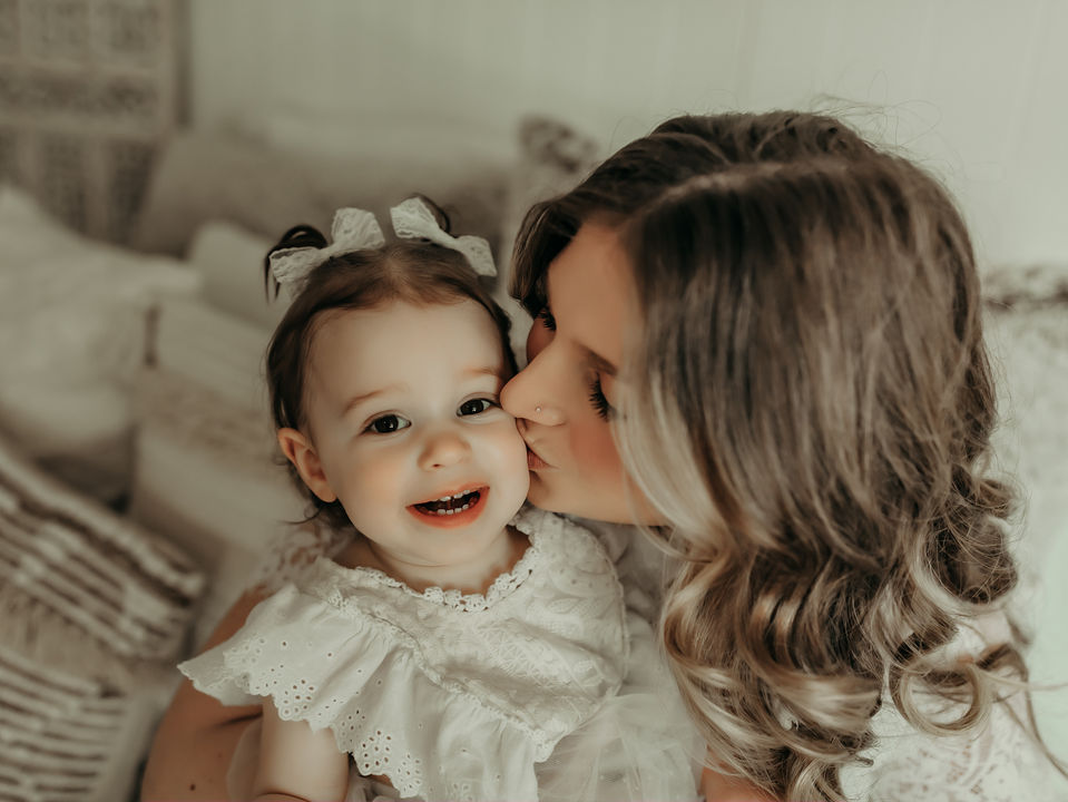 Mother kissing her smiling baby girl during a luxury milestone photography session at Elsiebel Photography serving Burnsville, Minneapolis, Edina, Eden Prairie, Maple Grove, and surrounding areas