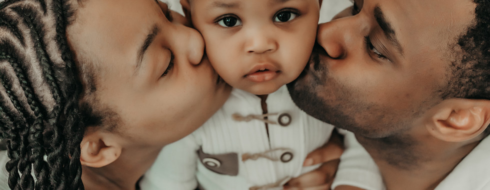 Parents kissing their one-year-old son during a timeless family cake smash photography session in Shoreview, MN