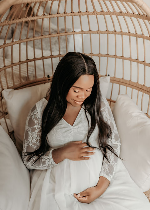 Mom-to-be sitting gracefully on bed — soft natural light maternity portraits Burnsville Minnesota.