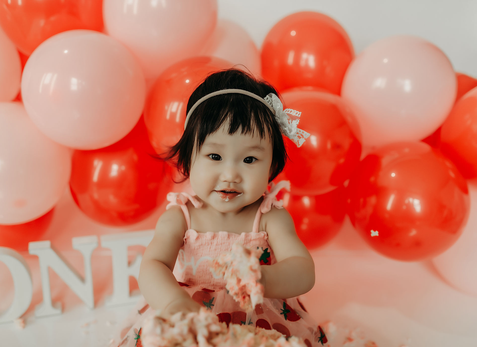 Baby girl smiling during her strawberry cake smash photography session near Minnetonka, MN