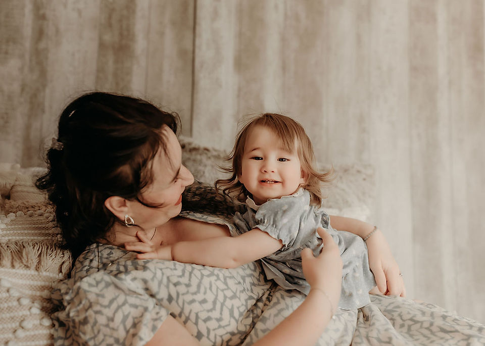 Mother playing with her daughter on a neutral bed during a natural lifestyle session by Elsiebel Photography serving Medina and the West Metro.