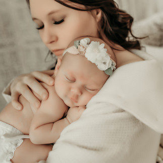 Baby girl stretching with a floral headband during her Maple Grove newborn session.