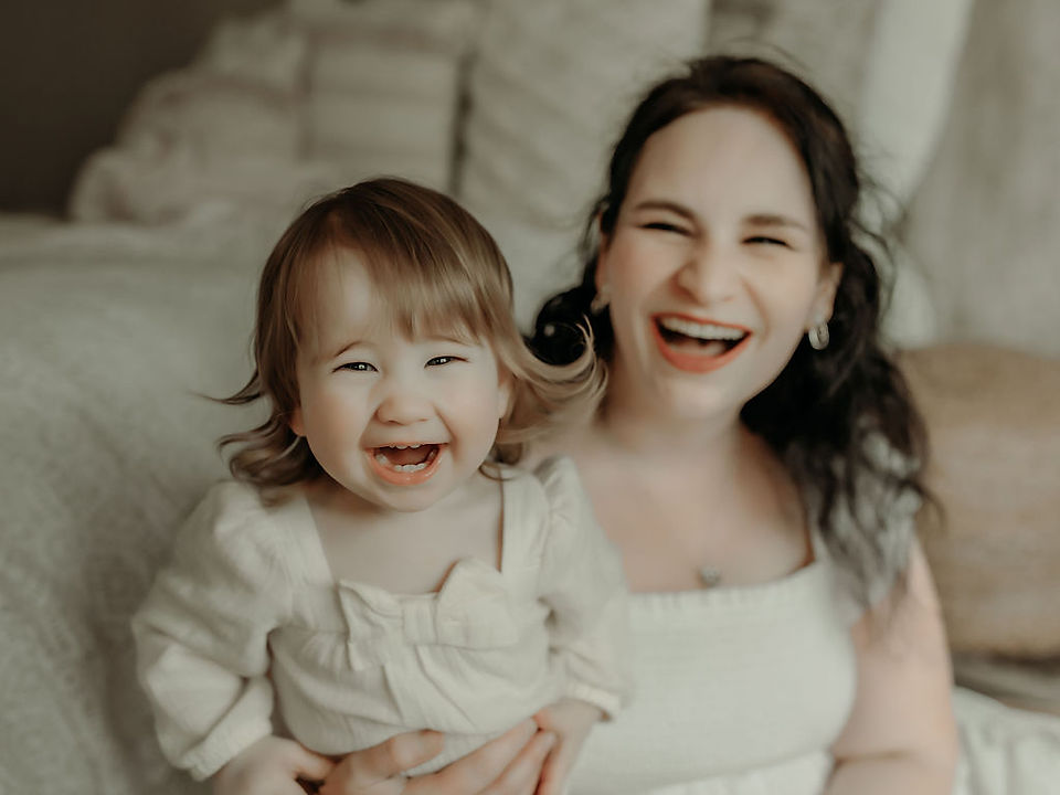 Mother smiling while holding her one-year-old daughter in a soft, neutral milestone portrait by Elsiebel Photography, luxury family photographer serving Medina, Minnesota.