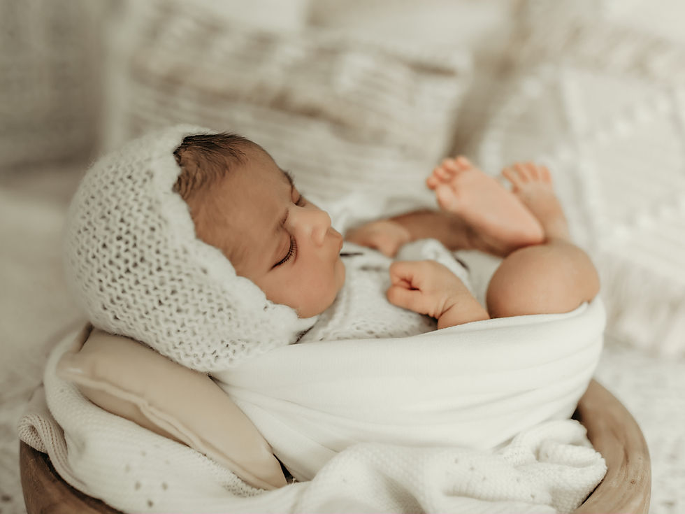 Newborn baby wrapped in a soft neutral blanket and knit bonnet during a luxury newborn photography session at Elsiebel Photography in Minneapolis serving Edina, Eden Prairie, Maple Grove, and surrounding areas