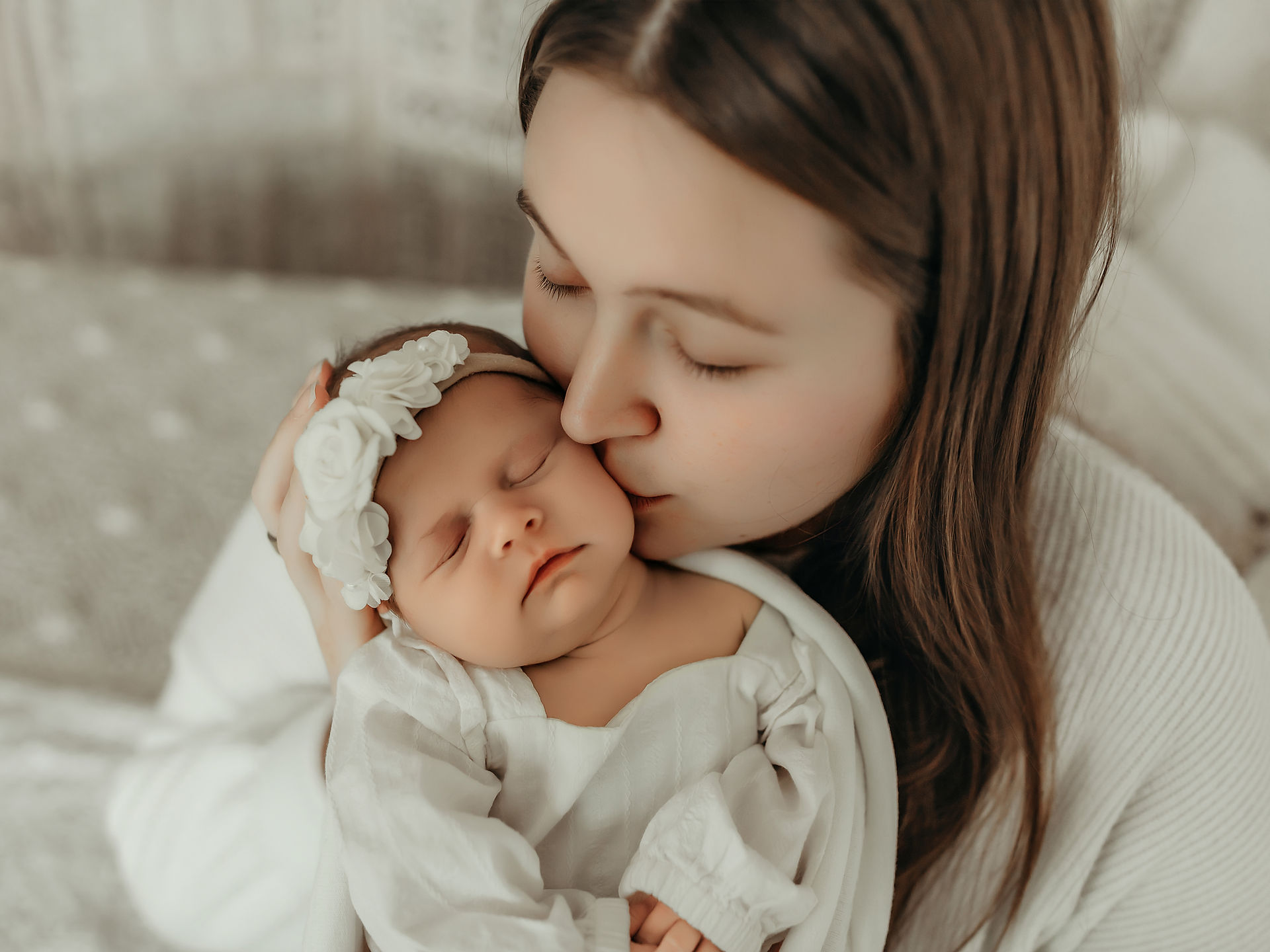 Mother cuddling and kissing her newborn baby girl during a timeless Minnesota newborn photography session.