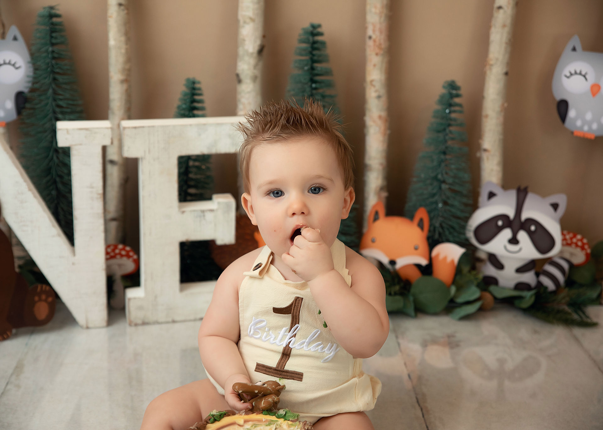 First birthday portrait with greenery, wood textures, and handcrafted smash cake