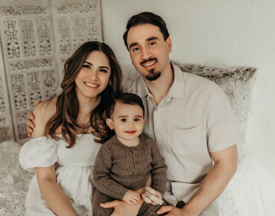 Elegant family portrait of smiling parents holding toddler during milestone photography session in Minneapolis studio by Elsiebel Photography.