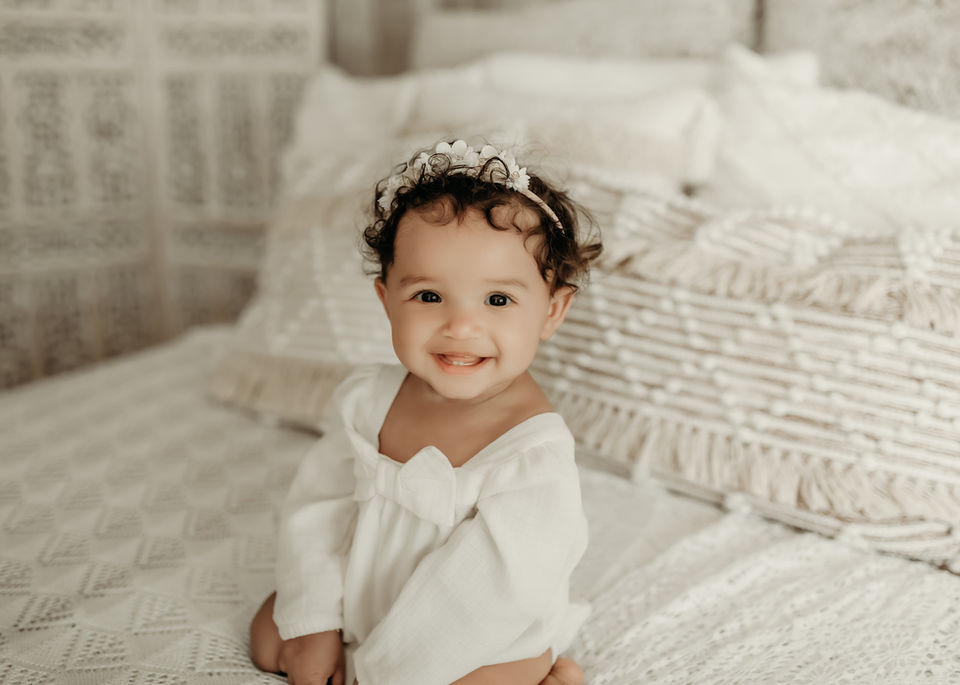 Smiling baby girl in a white outfit during a luxury milestone photography session at Elsiebel Photography serving Burnsville, Minneapolis, Edina, Eden Prairie, Maple Grove, and surrounding areas