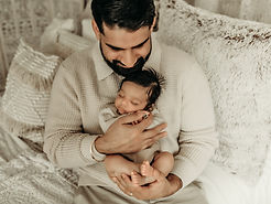 Intimate newborn portrait of a father holding his baby in a cozy, neutral setting, captured by Elsiebel Photography, a high-end Minneapolis newborn photographer.