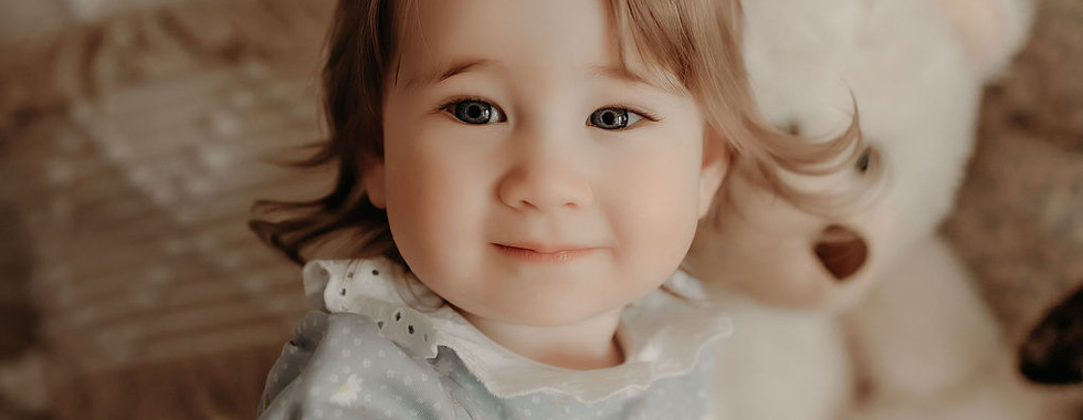 One-year-old girl smiling at the camera during a soft, natural milestone portrait session by Elsiebel Photography in the Medina Minnesota area.