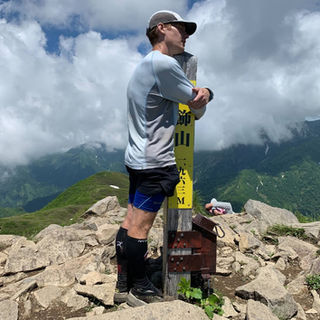 A hiker hugs the summit marker of Mt. Amakazari