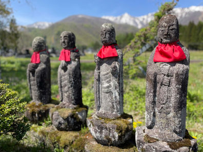 Old stone statues of Jozo stand guard along the Shionomichi (Salt Road) at the foot of the Alps in Hakuba