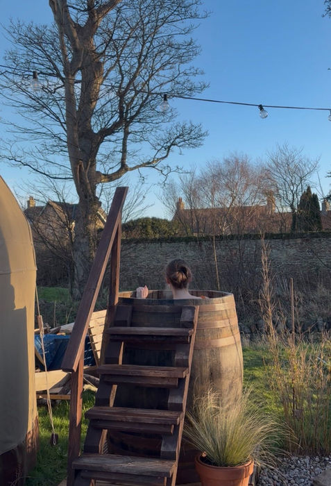 Body and Soul Retreat - Wooden steps lead to a barrel hot tub outdoors in bright sunshine.