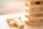 Wooden blocks stacked precariously, some fallen: risk and strategy