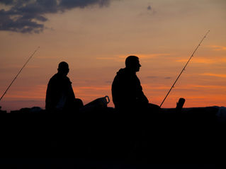 two men fishing at sunset
