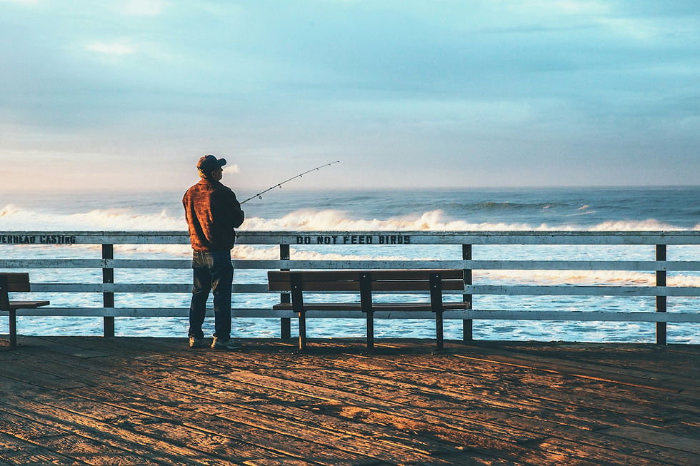 man looking fishing off pier