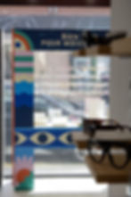 Vitrine de magasin avec texte "BIEN POUR MIEUX", affichage coloré et lunettes.