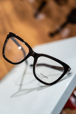 Lunettes noires œil-de-chat Yves Saint Laurent sur une surface blanche.