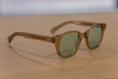 Lunettes de soleil à monture marron, verres verts, posées sur table.