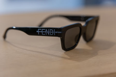 Lunettes de soleil noires FENDI posées sur une table en bois.