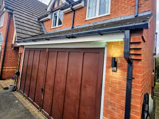 Red brick house with dark wood garage doors and gables