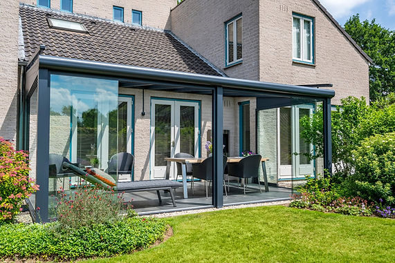 Modern dark metal veranda with glass sliding doors over a dark tiled patio, overlooking a lush green lawn and flower borders