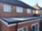A flat roof extension with a newly installed dark rubber membrane, black guttering, and white fascia boards attached to a brick house.