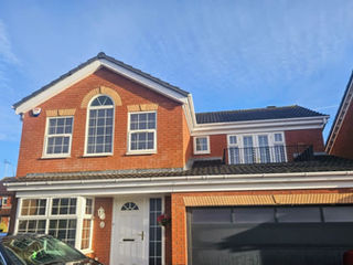 Modern red brick house with a large arched window.