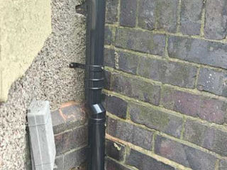 Black external drainpipe on a brick wall corner.