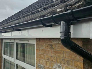 Black guttering and downpipe installed on a tiled roof