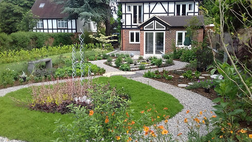 A beautifully landscaped garden pathway leading to a large residential brick house.
