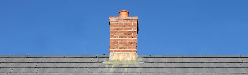 Brick chimney stack on tiled rooftop under clear sky