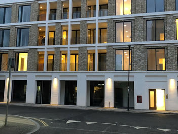 Exterior of a modern multi-storey commercial building with brightly lit ground floor