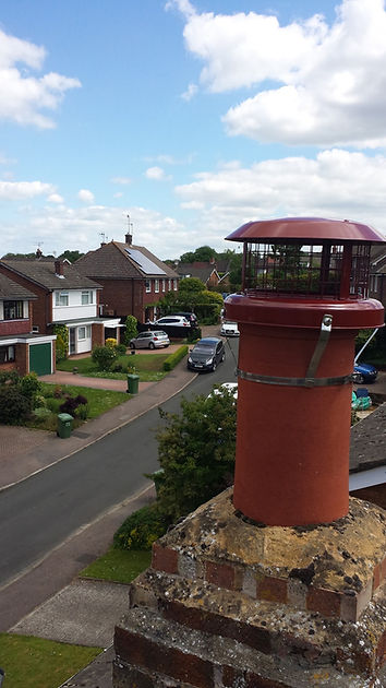 Red metal anti-downdraught chimney cowl fitted on a chimney pot