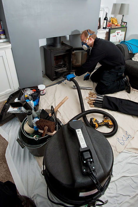 Chimney sweep wearing a dust mask using power sweeping rods at a fireplace