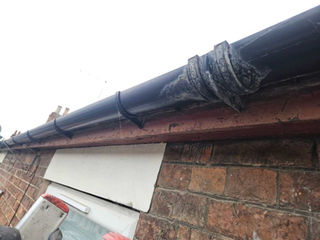 Black guttering installed on a brick house roofline.