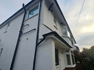 White two-story house with black gutters and bay window