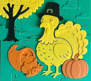 layered jigsaw puzzle depicting aThanksgiving scene with a turkey, pumpkin, and cornucopia