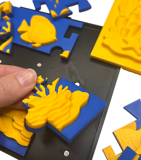 close up of fingers assembling a relief puzzle on top of its base/frame with part of comapnion template in background