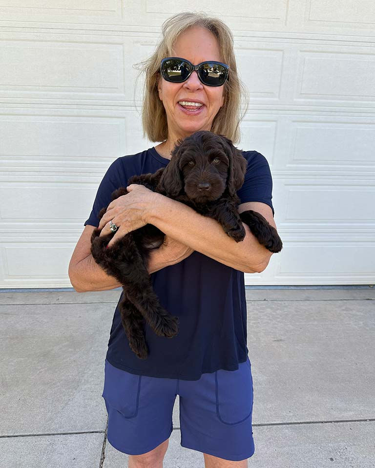 Woman holding a black Labradoodle in her arms