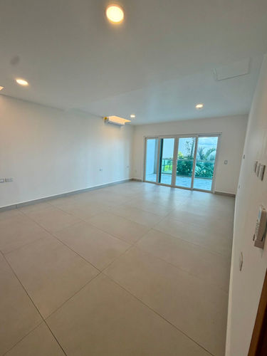Spacious empty living room in El Cantil—lots of natural light, balcony access.